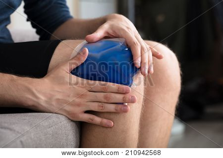 Close-up Of A Person Sitting And Applying Ice Gel Pack On An Injured Knee