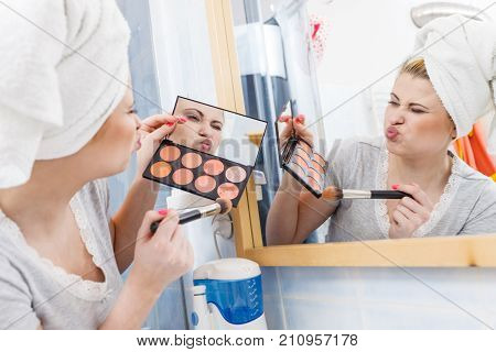 Woman In Bathroom Applying Contour Bronzer On Brush