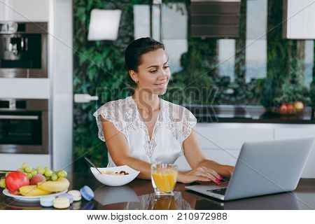 Portrait Of Beautiful Happy Woman Working With Laptop While Breakfast With Cereals And Milk. Eating