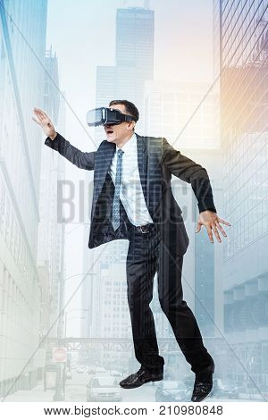Different dimension. Cheerful happy excited man wearing 3d glasses and moving his body while being absorbed into virtual reality