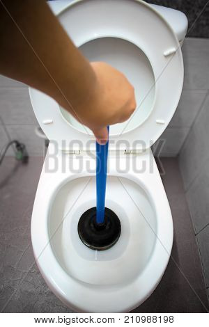 Plunger Clearing a Clogged Toilet in the Bathroom
