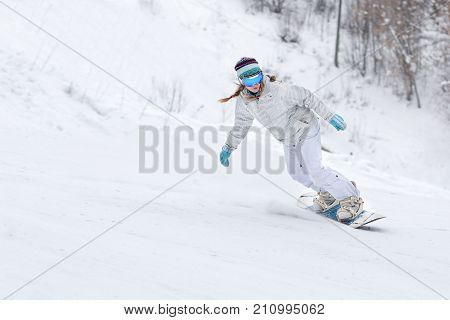Young woman snowboarder in motion on snowboard in mountains.