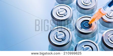 Group Of Vials With Punctured Syringe On Blue Table Top