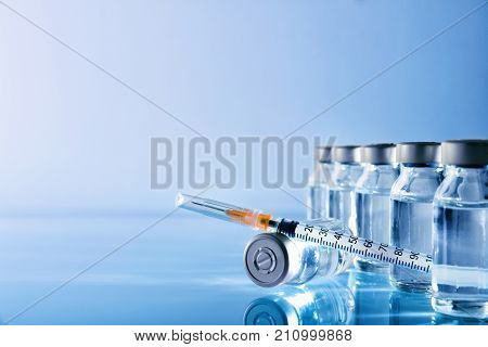 Vials Group And Syringe On Table With Blue Background