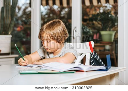 Cute Little Boy Doing Homework For School, Writing In Excersice Notebook