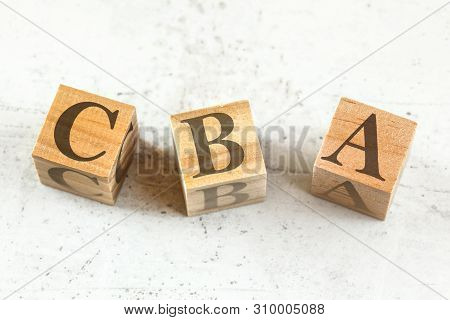 Three Wooden Cubes With Letters Cba Stands For Cost Benefit Assessment On White Board.