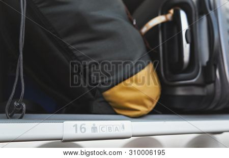 Detail On Seat And Rows Cba Sign Inside The Airplane, Overhead Locker With Blurred Baggage Above