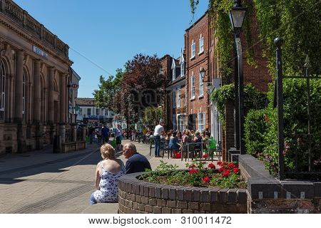 Beccles, United Kingdom - June 22, 2019: Couple Sat On A Stone Seat Enjoying A Lovely Sunny Day In B