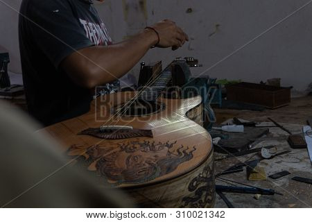 Gianyar,bali/indonesia-may 30 2019: A Classical Guitar Craftsman Is Pairing Guitar Strings To His Gu