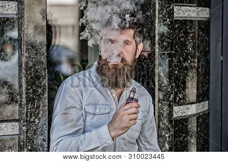 Bearded Man Smoking Vape. Man With Beard Breathe Out Smoke. Clouds Of Flavored Smoke. Smoking Electr