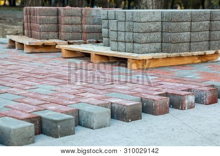 Paving The Footpath With Gray And Red Tiled Cubes.