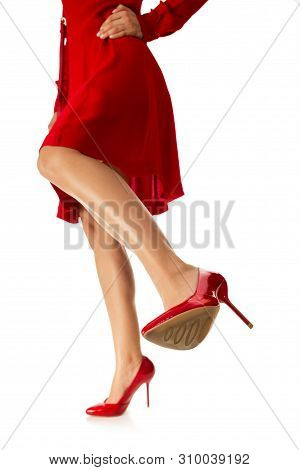 Woman Is Kicking. Girl In Red Dress Kicks With Her Leg In High Shoes To Camera On White Background