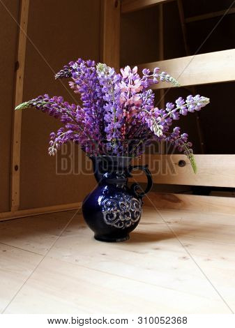 Bouquet Of Lupins In A Blue Vase On A Wooden Floor