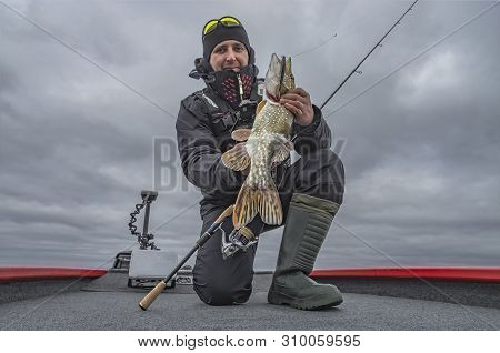 Pike Fishing. Happy Fisherman With Big Fish Trophy At The Boat With Tackles