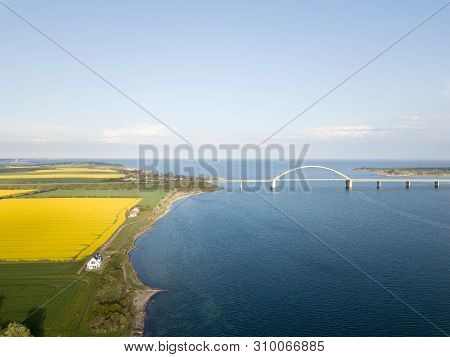 Fehmarn, Germany - May 9, 2019: Aerial Drone View Of Fehmarn Bridge And Yellow Rapeseed Fields.