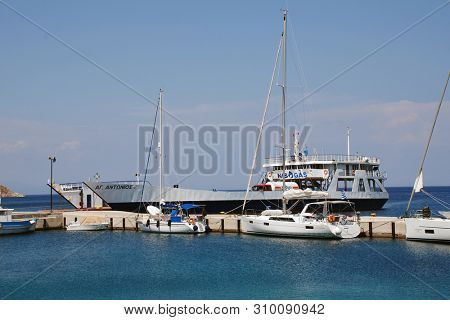 TILOS, GREECE - JUNE 12, 2019: Cargo ship Agios Antonios moored at Livadia harbour on the Greek island of Tilos. The 71.8mtr vessel was built in 1977 in Greece.