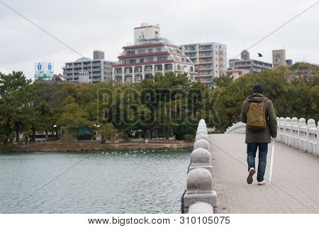 Fukuoka, Japan - January 1, 2019: A Man Carrying Backpack And Holding White Umbrella Walking On The 