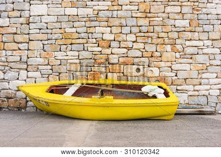 Old, Demolished Small Fishing Boat Against Stone Brick Made Wall. Fishery Obejcts.