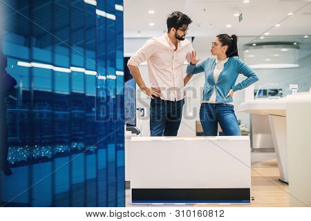 Attractive Hipster Young Couple Arguing In The Electronic Shop With Cartoon Box In Front With New El