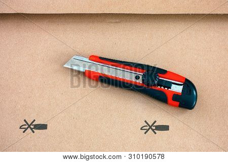 Red Paper Knife On Cardboard With Do Not Open With A Knife Sign. Close-up.