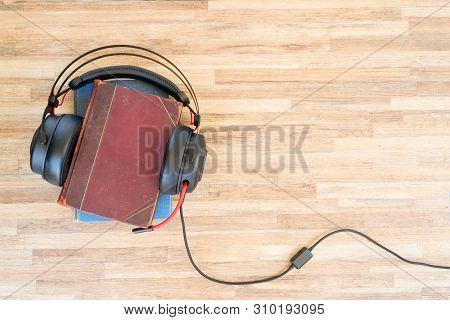 Audio Book Concept. Black Headphones And Books On Wooden Table. Top View With Copy Space.