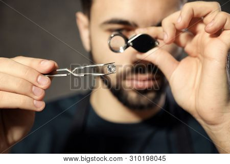 Male Jeweler Evaluating Precious Gemstone In Workshop, Closeup
