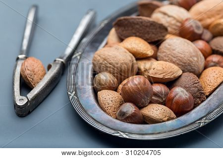 Different Kinds Of Nuts In Shell, Hazelnut, Walnut, Almond And Brazil Nuts On The Plate With Nut Cra