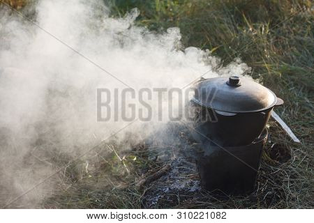 Close-up Of A Cauldron On The Fire Smokes On The Background Of Nature, The Concept Of Tourism And Hi