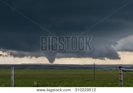 A Large Cone Tornado Under The Base Of A Dark Storm On The Plains In Wyoming.