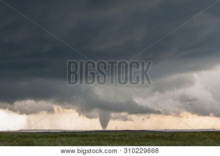 A Cone Tornado Touches Down Under The Base Of A Dark Storm On The Plains In Wyoming.
