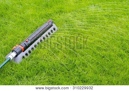 Irrigation System, Sprinkler Spaying Water Over Green Grass Lawn