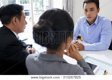Serious Young Vietnamese Businessman Talking To Human Resorces Managers At Meeting Devoted To His Di