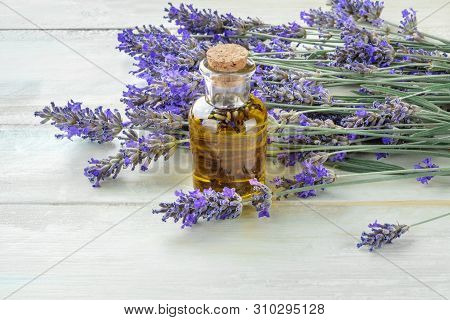 Lavender Essential Oil In A Glass Bottle With A Bouquet Of Fresh Blooming Lavender Flowers On A Rust