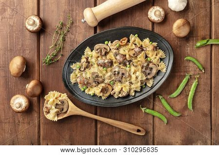 Mushroom And Cheese Pasta. Farfalle With Cremini And Green Peas, Shot From The Top With Ingredients 