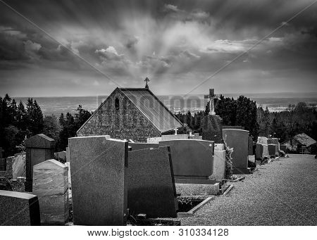 Black And White Rendering Of Graveyards In Cemetery And Sun Rays Converging On Top Of A Church Cross