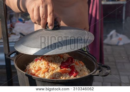 Cooking Tasty Pilaf In Nature. Cooking Pilaf In Big Cauldron On Fire At Picnic. Cooking Pilaf In A P