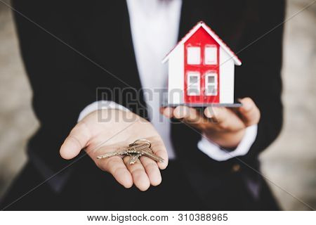 Agent Businessman In White Shirt Holding Keys In Hand A Small House And Apartment
