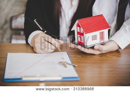 Estate Agent Giving House Keys To Female And Sign Agreement In Office