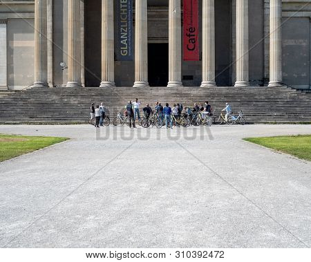Munich, Bavaria, Germany - May 18, 2019. Tourists On Bicycles Listen To A Guide In Front Of The Anti