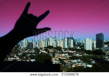The View Of The Punk Rock Hand Placed On The Window With The View Of Skyscrapers In The Day And Pink
