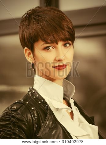 Happy young fashion woman walking on city street Stylish female model in black leather jacket with pixie hair style