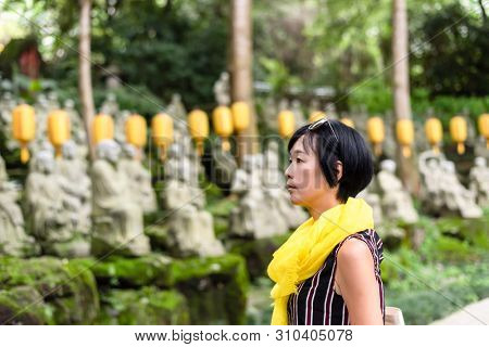 traveling modern Asian woman at a garden with arhat stone statues