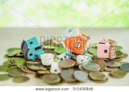 Mini House On Pile Of Coins With Green Blur Background.