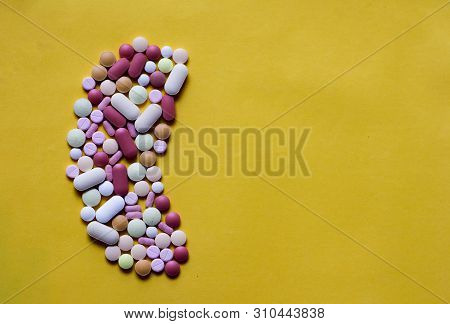 Medicine Pills Tablets Capsules In Shape Of Human Kidney In Yellow Background With Space For Text