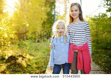 Two Cute Young Sisters Having Fun During Forest Hike On Beautiful Summer Day. Children Exploring Nat