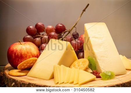 gruyere cheese with variety of fruit and cracker on wooden plate in buffet line