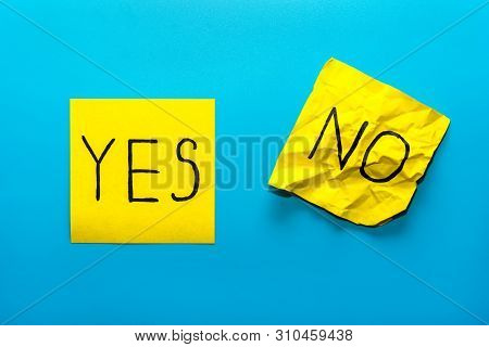 Close Up Black Handwritten Inscription Yes And No Word On Two Yellow Square Stickers On Blue Backgro