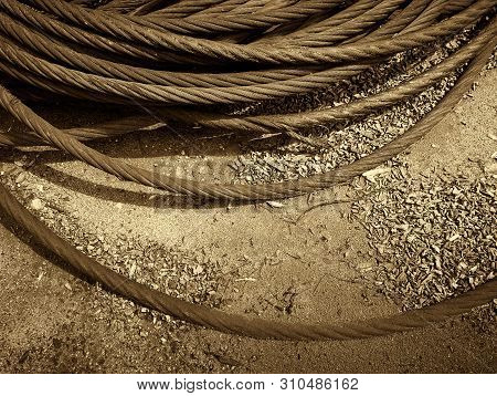 Old Rusty Strong Cable Rolled Into The Bay. The Rings Of Iros Are Located On The Ground, The Yard Of