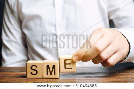 Businessman Holds Wooden Blocks With The Word Sme. Small And Medium-sized Enterprises - Commercial E