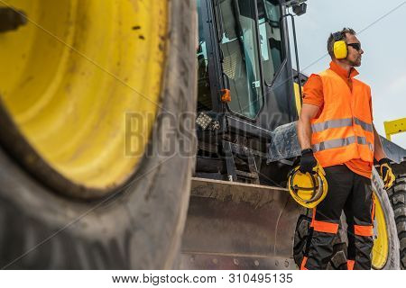 Road Construction Business. Caucasian Heavy Machinery Operator In His 30s With Noise Reduction Headp